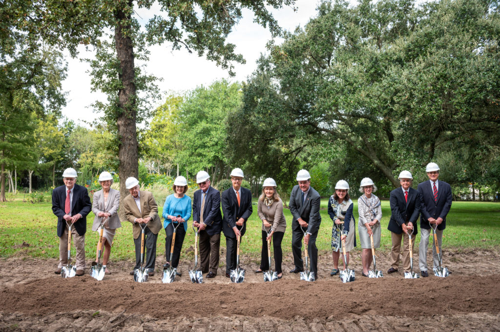 Men and women with shovels breaking ground on the construction of a new building